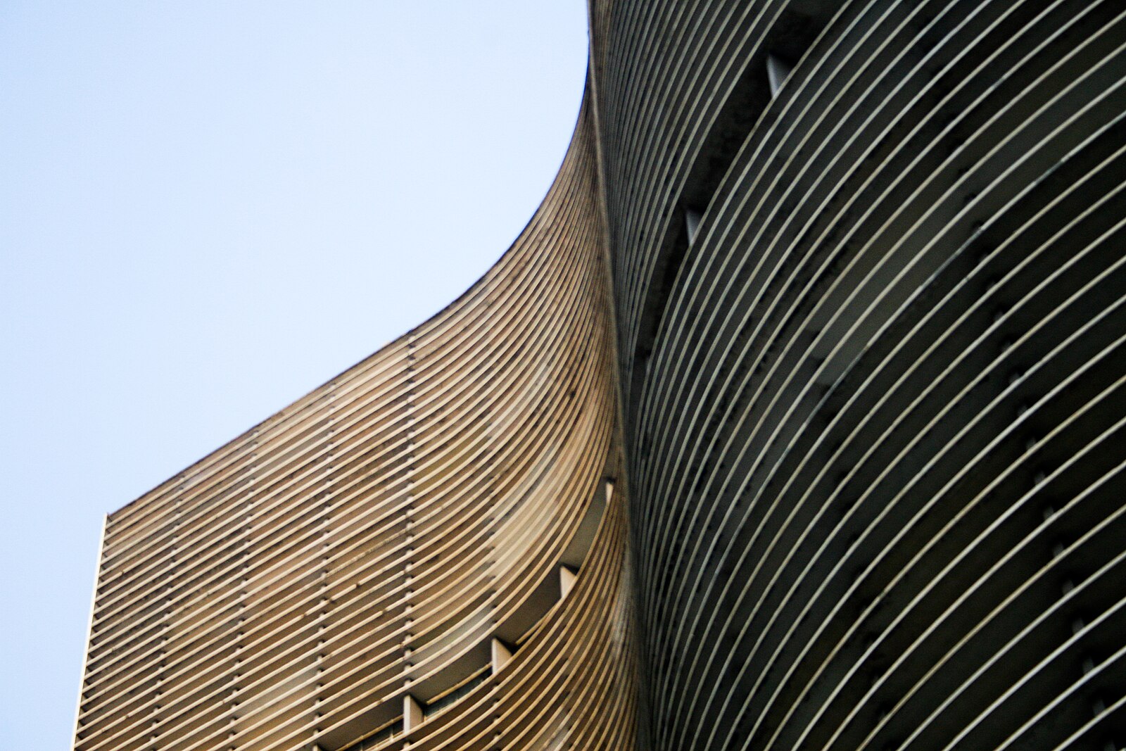 仰视 Edifício Copan 的弧形立面，画面突出建筑的水平线条