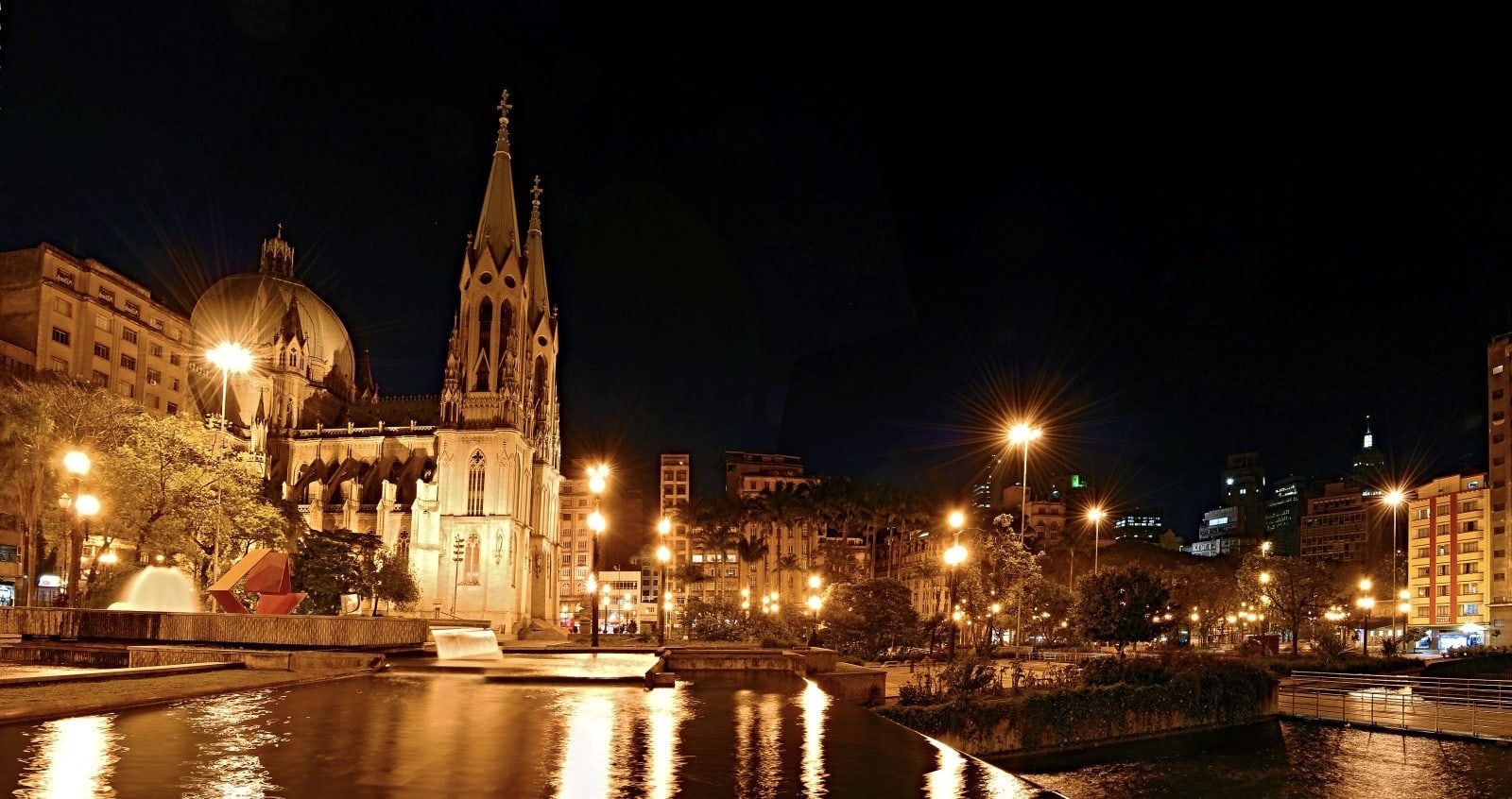 Praça da Sé 的夜景全景，画面包括主教座堂、镜面水池与城市天际线